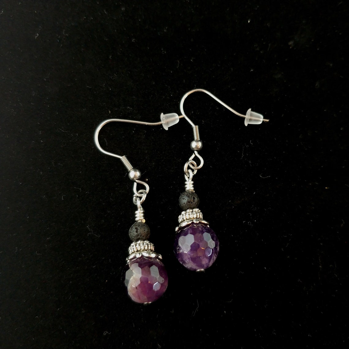 Eyrnalokkar með Amethyst steinum og minni lava steinum liggandi á svörtum bakgrunn